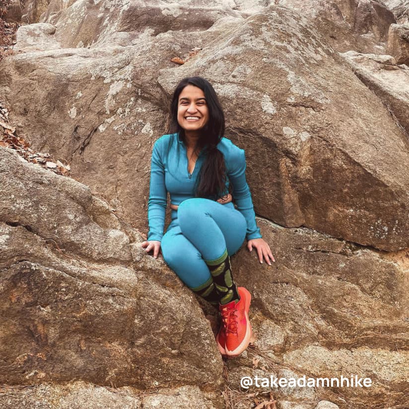 A person sitting on a boulder and smiling